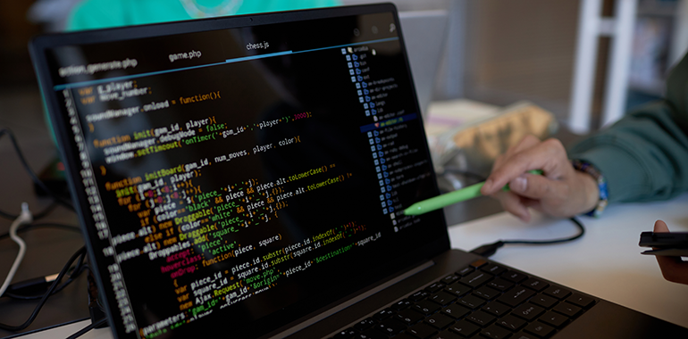 focus-on-laptop-screen-with-coded-data-and-pen-hel-2025-02-11-15-42-45-utc